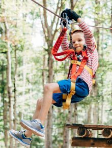 Boy goes down the zip line holding on to the insurance with his hands. High quality photo